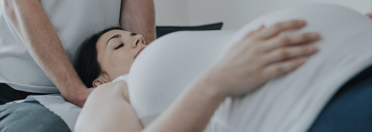 A pregnant woman lies on a physio bed