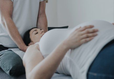 A pregnant woman lies on a physio bed